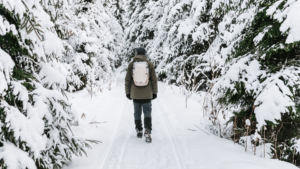 man with backpack exploring canada winter trail
